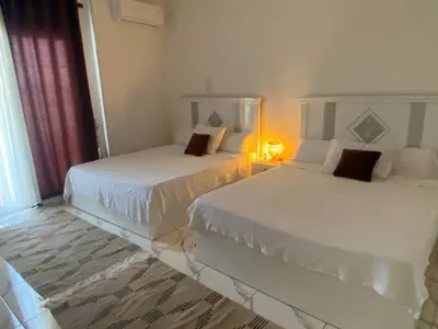 two white beds in a room with a window at Asmara Apartment Hatshepsut in Naj‘ al Madāmūd