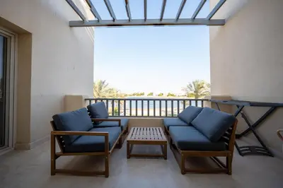 a balcony with two blue chairs and a table at Joubal 2BR • Top Floor Lagoon View in Hurghada