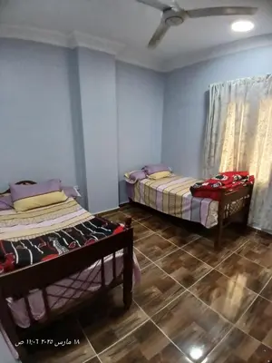 two beds in a room with blue walls and wooden floors at Hotel apartments in Hurghada