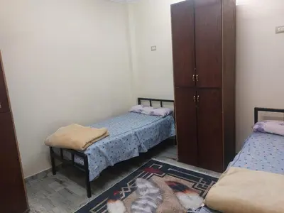 a bedroom with two beds and a cabinet and a rug at Horus apartment in Al Bayāḑīyah