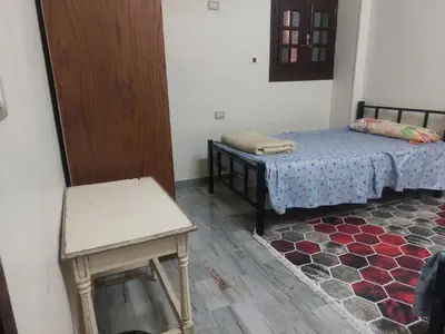 a room with two beds and a table and a door at Horus apartment in Al Bayāḑīyah