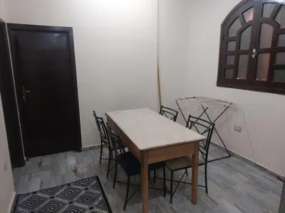 a table and chairs in a room with a black door at Horus apartment in Al Bayāḑīyah