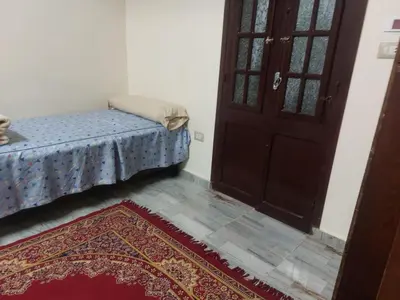 a bedroom with a bed and a door and a rug at Horus apartment in Al Bayāḑīyah