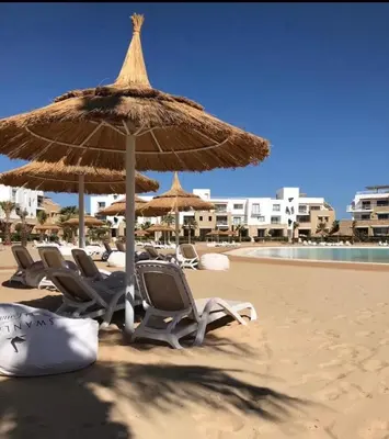 a group of chairs and an umbrella on the beach at Hotel apartment swan lake in Hurghada