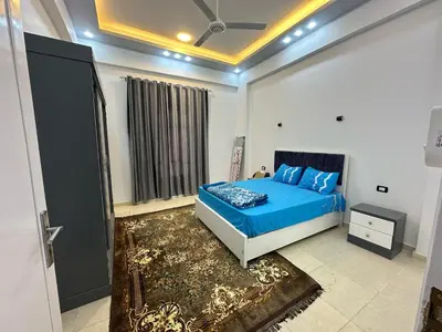 a bedroom with a blue bed and a window at Nsma house in Al Aqālitah