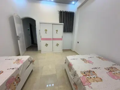 a bedroom with two beds and a cabinet at Nsma house in Al Aqālitah