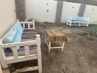 a group of beds and a table in a yard at Nsma house in Al Aqālitah