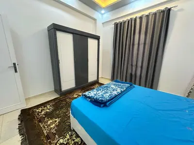 a bedroom with a blue bed and a window at Nsma house in Al Aqālitah