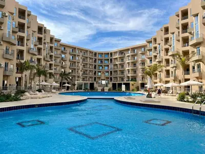 a swimming pool in front of a large apartment building at Beachfront Bliss - Your Hurghada Escape Awaits in Hurghada