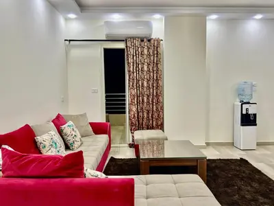 a living room with a red couch and a table at Beachfront Bliss - Your Hurghada Escape Awaits in Hurghada