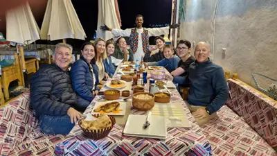 a group of people sitting around a table with food at Zena Toma Nubian Guest House in Aswan