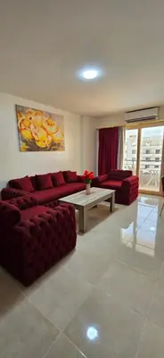 a living room with a red couch and a table at Tiba Golden Marina Bay Hurghada in Hurghada