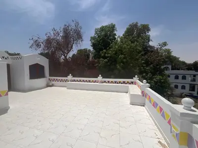 a large patio with a white fence and trees at Toto Kato in Jazīrat Aswān