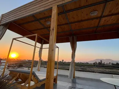 a bed on a roof with the sunset in the background at Nile Spirit Sunrise in Luxor
