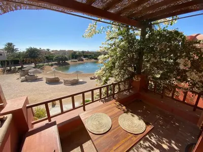 a wooden table on a balcony with a view of a pool at Apartment at Upper Nubia lagoon El Gouna in Hurghada
