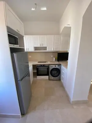 a small kitchen with white cabinets and a dishwasher at Apartment at Upper Nubia lagoon El Gouna in Hurghada