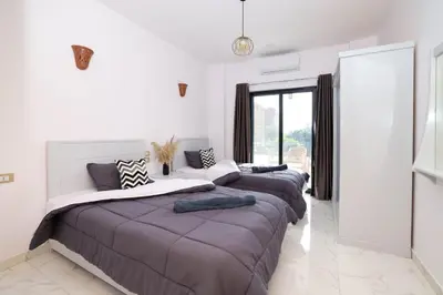 a bedroom with three beds and a large window at Serenity House Luxor in Luxor