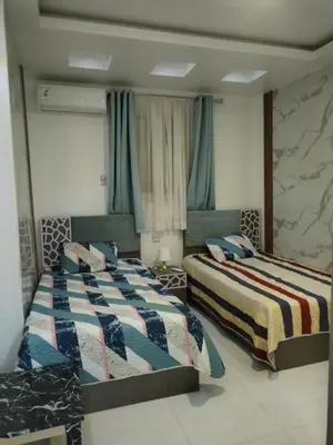 two beds sitting in a room with blue curtains at Al Khaother in Hurghada