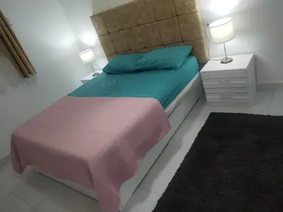 a small bedroom with a bed with green and pink sheets at Al Khaother in Hurghada