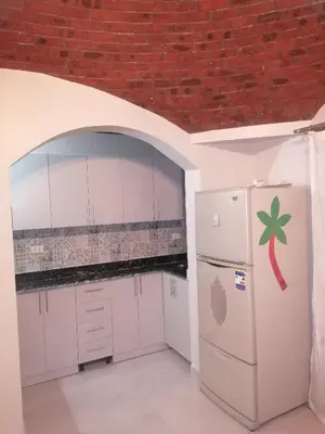a kitchen with white cabinets and a brick wall at 265 Apartment in Hurghada