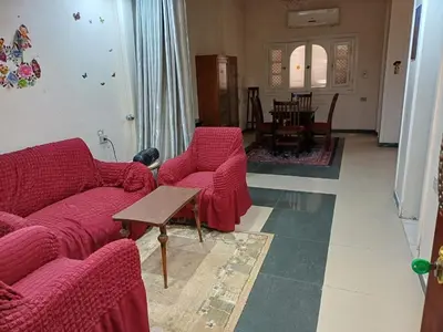 a living room with two red couches and a table at Ahmeds in Luxor