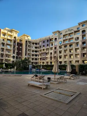 a large building with chairs and umbrellas in a courtyard at Florenza Khamsin Lux Apartment in Hurghada