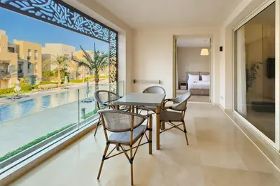a dining room with a table and chairs and a large window at Neat & Neutral 1BDR Pool front Mangroovy in Hurghada