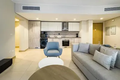 a living room with a couch and a blue chair at Neat & Neutral 1BDR Pool front Mangroovy in Hurghada