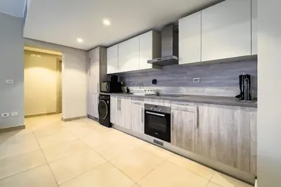 a large kitchen with white cabinets and a dishwasher at Neat & Neutral 1BDR Pool front Mangroovy in Hurghada