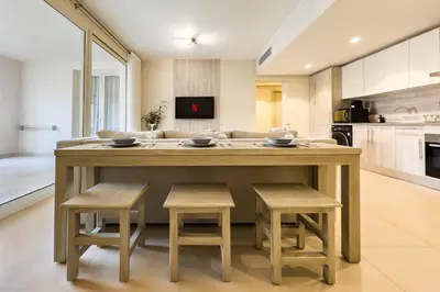 a kitchen with a large wooden table and stools at Neat & Neutral 1BDR Pool front Mangroovy in Hurghada
