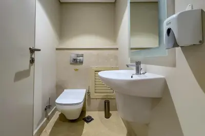 a bathroom with a white sink and a toilet at Neat & Neutral 1BDR Pool front Mangroovy in Hurghada