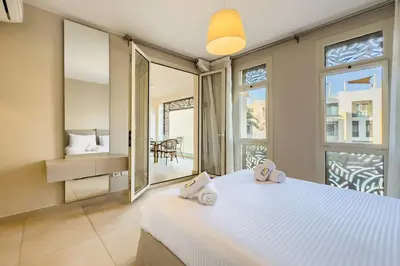 a bedroom with a large white bed and a balcony at Neat & Neutral 1BDR Pool front Mangroovy in Hurghada