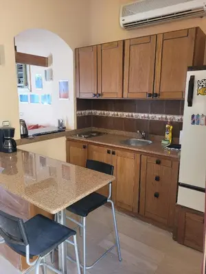 a kitchen with wooden cabinets and a table with chairs at Charming Studio in Downtown El Gouna in Hurghada