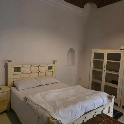 a bedroom with a large bed with white sheets at Sahara palace in Luxor