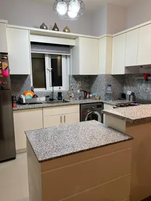 a kitchen with white cabinets and a granite counter top at lovely 2 bedrooms Groundfloor in Hurghada