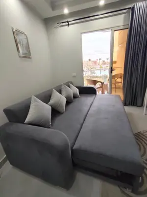 a large black couch in a living room with a window at Scandic Resort in Hurghada