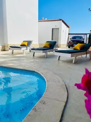 two benches with yellow pillows next to a swimming pool at Magawish Hurghada Studio 7 in Hurghada