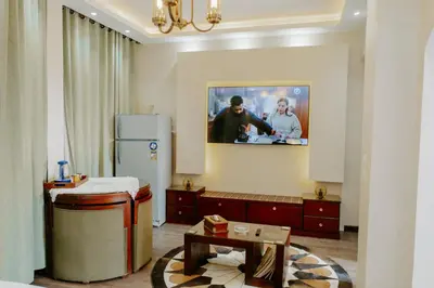 a living room with a refrigerator and a table at Aton Suites Luxor Resort East Bank Nile View in Luxor