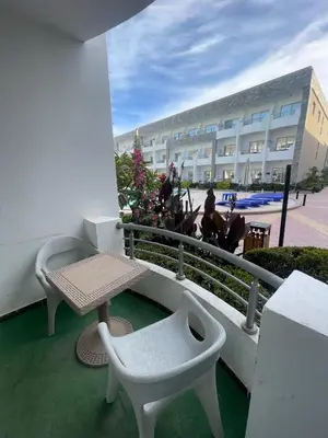 a balcony with a table and a bench and a building at Steps from Beach & Near Airport Furnteched, Kitchenette, full APT Free WIFI in Hurghada