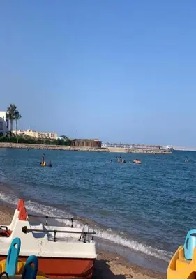 a boat on the beach with people in the water at Steps from Beach & Near Airport Furnteched, Kitchenette, full APT Free WIFI in Hurghada
