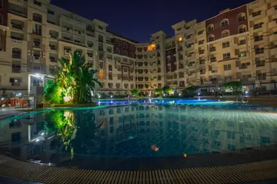 a large pool in front of a building at night at Florenza Khamsin in Hurghada