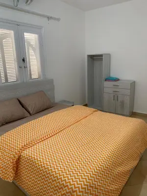 a bed with an orange comforter in a bedroom at Tala 1 in Hurghada