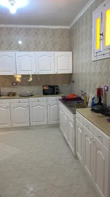 a kitchen with white cabinets and a tile floor at Tala 1 in Hurghada