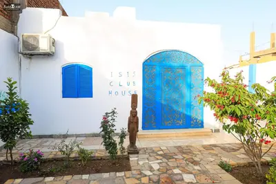 a blue door on a white building with flowers at Isis Club House in ‘Ezbet Abu Ḥabashi