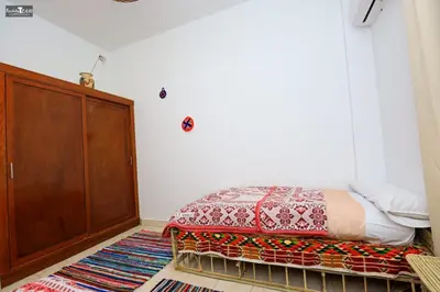 a bedroom with a bed and a wooden cabinet at Isis Club House in ‘Ezbet Abu Ḥabashi