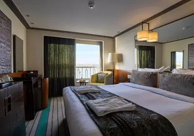 a hotel room with a large bed and a window at Luxor Or Aswan Nile Cruise, Ultra Deluxe Cruises sailing 3, 4, Or 7 Nights in Luxor