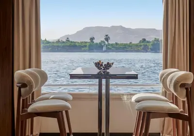 a table with chairs and a view of the water at Luxor Or Aswan Nile Cruise, Ultra Deluxe Cruises sailing 3, 4, Or 7 Nights in Luxor