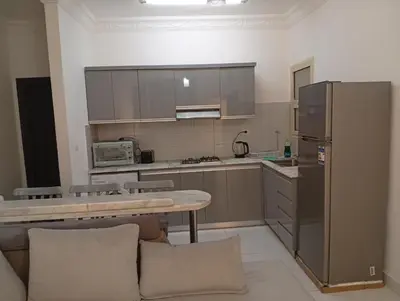 a kitchen with a table and a refrigerator at Lägenhet i villa med pool i Hurghada-Magawish in Hurghada