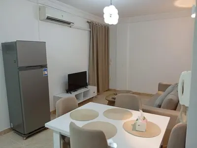 a living room with a white table and a tv at Lägenhet i villa med pool i Hurghada-Magawish in Hurghada
