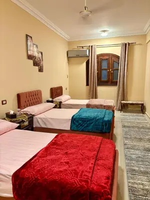 a hotel room with three beds with red and blue sheets at Nile View House in Aswan